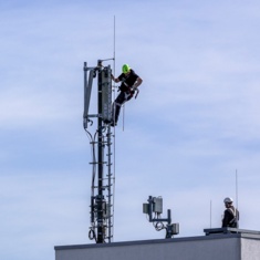 Techniker bauen einen 5G Standort auf einem Hausdach auf.