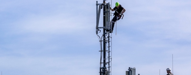 Techniker bauen einen 5G Standort auf einem Hausdach auf.