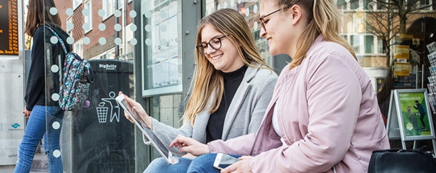 Bürgerinnen und Bürger profitieren an einer Bushaltestelle vom schnelleren Mobilfunkausbau in Münster